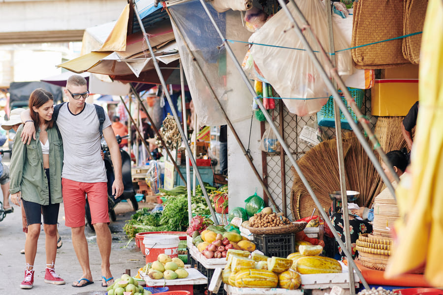 Una pareja de turistas camina por un mercado chino de frutas y verduras