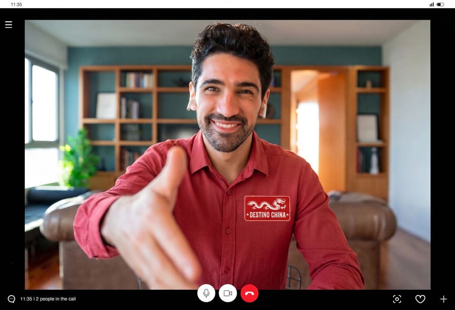 Un asesor de viajes de la agencia Destino China sonriendo a la cámara durante una videollamada